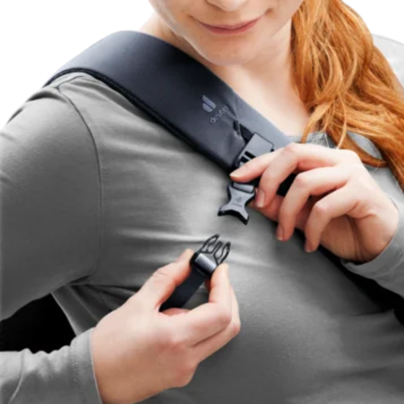Woman adjusting a black backpack strap on a plain background
